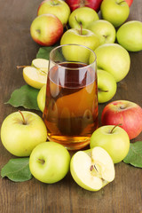 Useful apple juice with apples around on wooden table