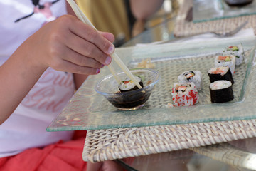 Fototapeta na wymiar Girl dipping sushi