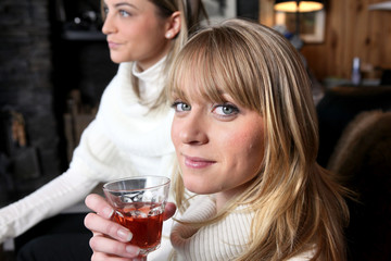 Two female friends relaxing at home with glass of wine