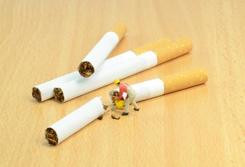 Stop smoking concept with workman sawing cigarettes in half
