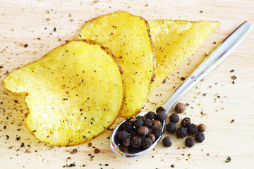 Homemade potato chips with pepper with a spoon peppercorns on the side