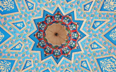 12 pointed blue and gold Islamic star pattern carved in wood on the ceiling of a Madrassa near Bukhara, Uzbekistan.