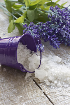 Sea salt in little bucket with lavender on white  wooden backgro