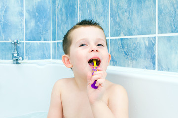 Little boy in the bath tub brushing his teeth