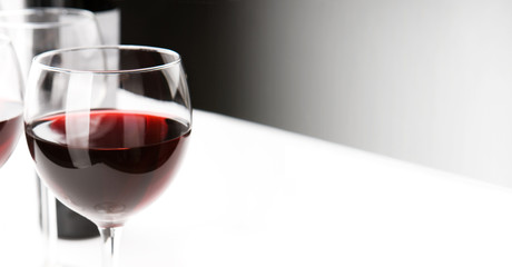 Glasses of red whine on white table cloth.