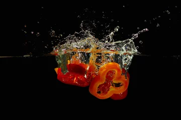 Photo sur Plexiglas Éclaboussures deau Tranches de poivrons rouges et jaunes tombant dans l& 39 eau