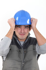 Scared builder holding hat