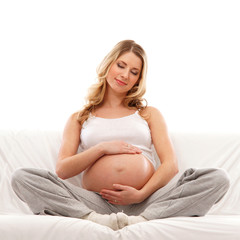 Fototapeta na wymiar Młodych blond kobieta w ciąży siedzą w zamkniętych ubrania