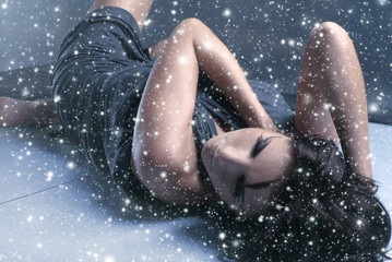 A young woman laying in a dress on a snowy background