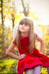 Sweet girl in the autumn forest sitting on a chair