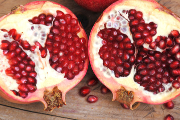 Pomegranate fruit halves on rustic background