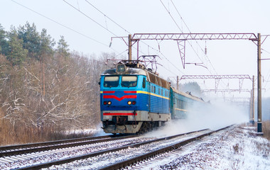 Fototapeta premium Passenger train rapidly moving along the snow track