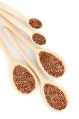 flax seeds in wooden spoons on white background close-up
