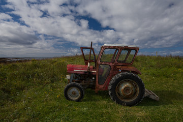 Rusty old red tractor by the sea