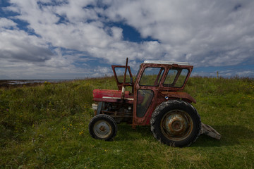 Rusty old red tractor by the sea