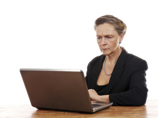 Mature woman sitting by table working on notebook computer