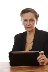 Mature woman sitting by table with tablet computer