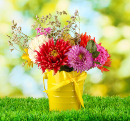 Bright yellow bucket with flowers on green background