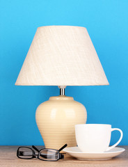 table lamp with cup and glasses on blue background