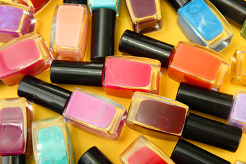 Group of bright nail polishes, on yellow background