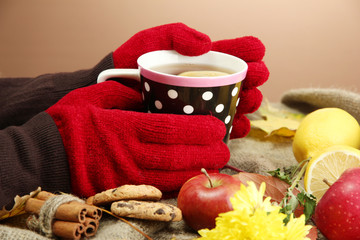 hands holding cup of hot drink and autumn leaves,