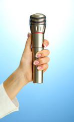 female hand with microphone, on blue background
