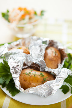 Potatoes in foil not a white plate and a bowl of salad