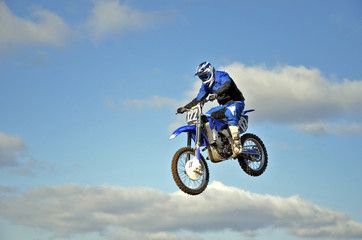 Fototapeta na wymiar Flight of biker motocross przeciw błękitne niebo i chmury