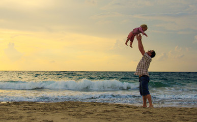 father and daughter playing together on the beach at sunset