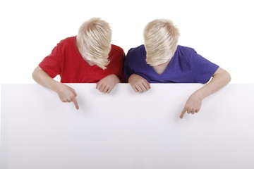 Zwei blonde Zwillinge über leerem Plakat schauen nach unten