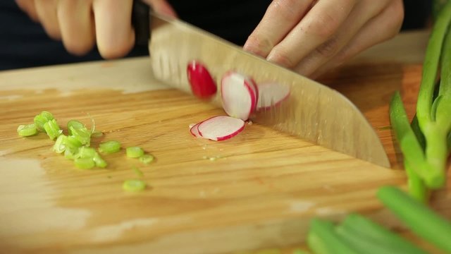 Dolly shot of female hands cutting radish in kitchen