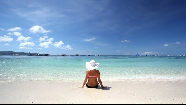 Woman in sun hat relaxing on tropical beach