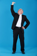 mature man in suit touching ceiling against blue background