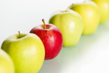 Red apple standing out from row of green apples.
