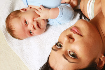 Loving mother with her infant child in bed. Top view