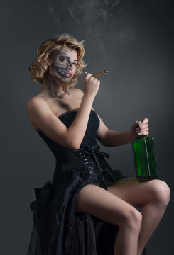 Portrait of drinking and smoking woman with painted skull
