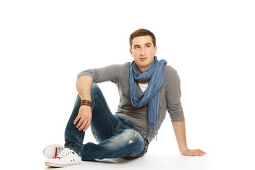 Pensive stylish young man sitting on floor