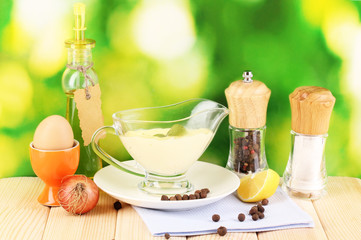 Mayonnaise in bowl on wooden table on nature background