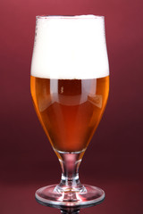 Glass of beer on pink background