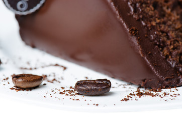 Dark chocolate cake with coffee beans on white plate close up