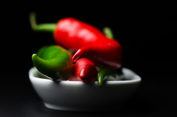 Cayenne pepper in white plate on dark background close up