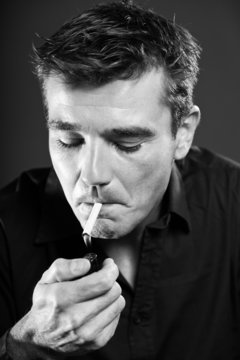 Smoking man with short brown hair. Black and white studio shot.