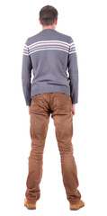 Fototapeta premium Back view of handsome man in sweater and jeans looking up.