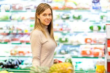 Smiling woman shopping with trolley in supermarket