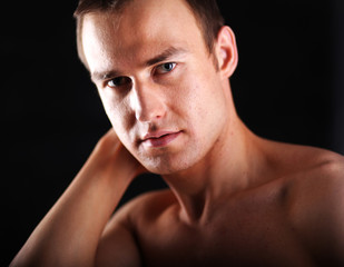 Fototapeta premium Portrait of a naked muscular man, isolated on black background