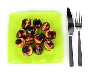 roasted chestnuts in the green plate with fork and knife