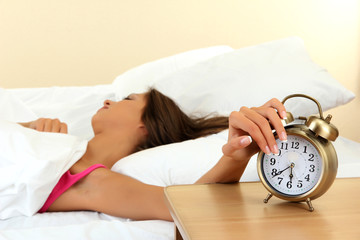 young beautiful woman in bed and alarm clock