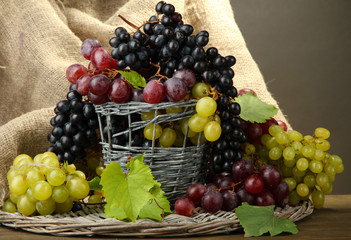 assortment of ripe sweet grapes in basket, on grey background