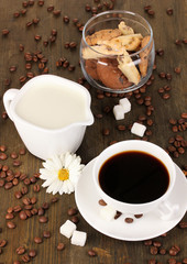 A cup of strong coffee and sweet cream on wooden table close-up