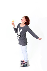 Smiling fat girl standing on the scale and holding a cake